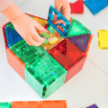 Child placing a blue TileTek triangle tile onto a block box holding toy figures