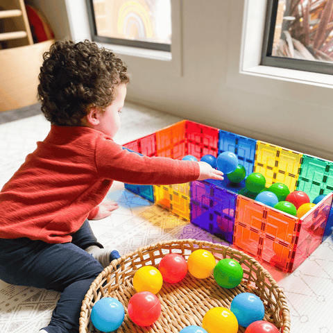 Child reaching into a colourful ball pit built from TileTek large square tiles