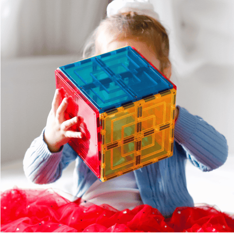 Child holding a red, blue and yellow TileTek large square tile cube to their face