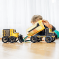 Child tipping the bed of a magnetic tile dump truck beside an assembled bulldozer