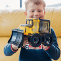 Child holding an assembled magnetic tile bulldozer with oversized wheels