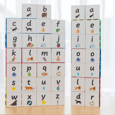 Two stacked towers of Tile Tek lower-case alphabet toppers showing the full 40-piece set