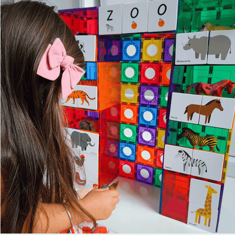 Child looking at a magnetic tile zoo tower decorated with Tile Tek animal toppers