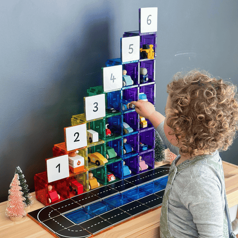 Child pointing to Tile Tek numeral toppers on a rainbow magnetic tile staircase