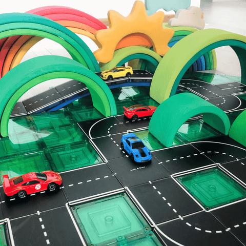 Toy cars driving along Tile Tek road toppers on green magnetic tiles