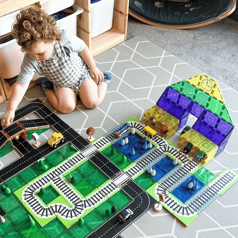 Child playing beside a magnetic tile train station built with Tile Tek toppers
