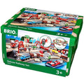 A green storage box displays an image of the Brio World Deluxe Railway Set on its sides. The set, part of the BRIO World collection, includes various train components, railway tracks, bridges, and accessories suitable for children aged 3 and up. The image depicts a colorful and detailed train scene featuring a motorized Metro city train.