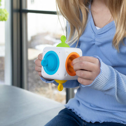 Child holding the colourful Fat Brain Tugl Cube