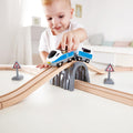 Child playing with the Hape Passenger Train Set train crossing the bridge