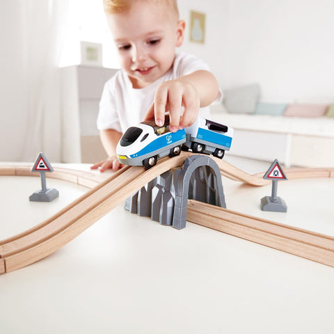 Child playing with the Hape Passenger Train Set train crossing the bridge