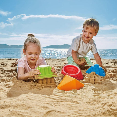 Two children playing on the beach with Hape Sand toy moulds