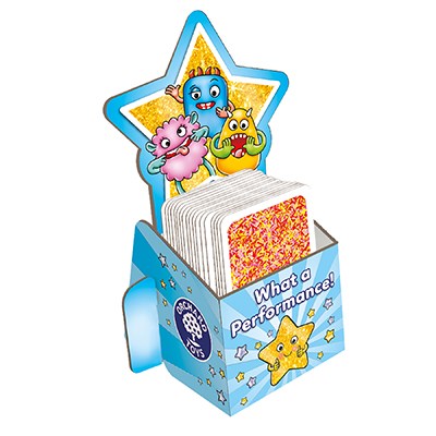 A colorful box with a star shape at the top showcases three cartoon characters: a blue monster with outstretched arms, and two smaller monsters, one pink and one yellow. The family board game box is filled with activity cards and reads "Orchard Toys What a Performance Game" from Orchard Toys.