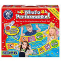 The image shows the box of Orchard Toys' family board game called "What a Performance!" The red box, decorated with yellow stars and a spinner in the top left corner, features children performing various actions accompanied by instructions such as "Act," "Spin," and "Say." It includes 300 hilarious challenges and activity cards.