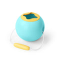 The QUUT Mini Ballo Bucket - Banana Blue by QUUT features a turquoise spherical container with a yellow lid that includes an opening, and a white cord attached to a yellow handle. The smart design includes soft-touch finishing, preventing spills while ensuring easy carrying and storage.