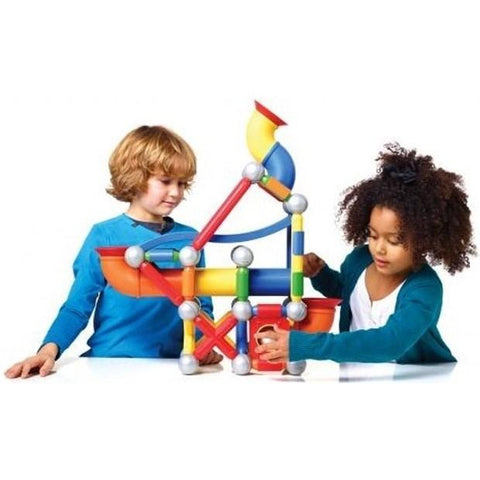Two children are playing with a vibrant SmartMax Mega Ball Run magnetic construction set. The toy includes 71 pieces, featuring various shaped parts connected by silver magnetic balls, coming together to form a tall structure. The children are smiling and focused on building and adjusting their Mega Ball Run.